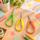 Ciseaux ergonomiques Easy-Grip pour enfant de 13,5 cm, vert, jaune et orange, sur un bureau créatif.